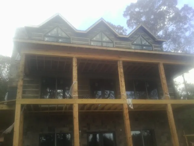 Dormers and porch framing on a large log home under construction — Roof Coating work by our crew in Williamson
