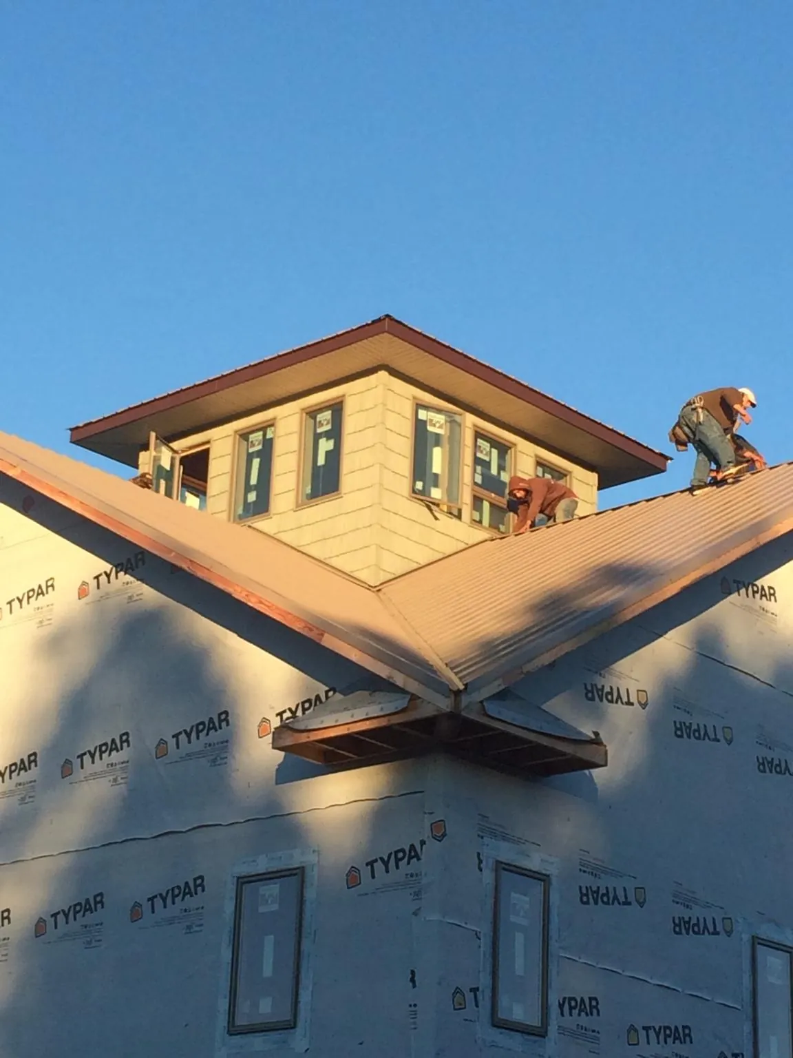 Roofers working around a rooftop cupola on a new metal roof at sunset — Roof Waterproofing in Williamson by Roofing Brothers